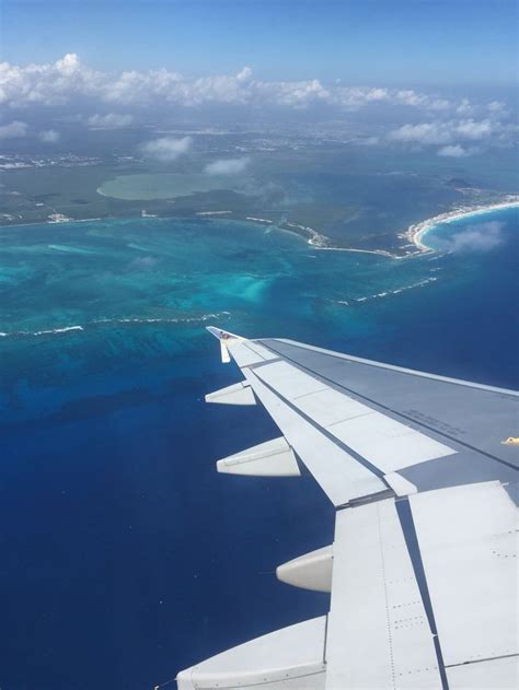 An Airplane Wing Flying Over The Ocean And Coral Reef In The Distance