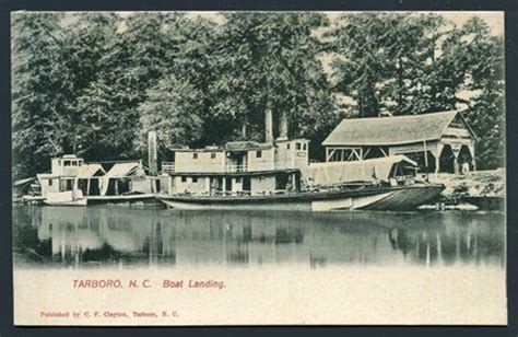 an old photo of some boats docked at a dock in the water with houses on ...