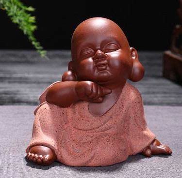 A Small Buddha Statue Sitting On The Ground