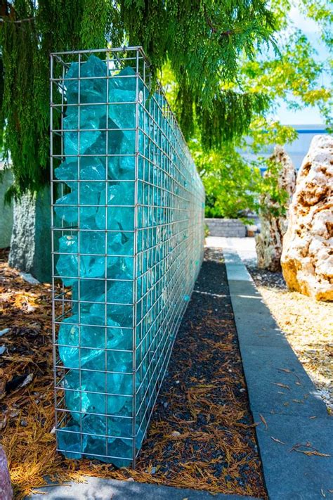 a blue glass block sitting on the side of a road next to a rock wall