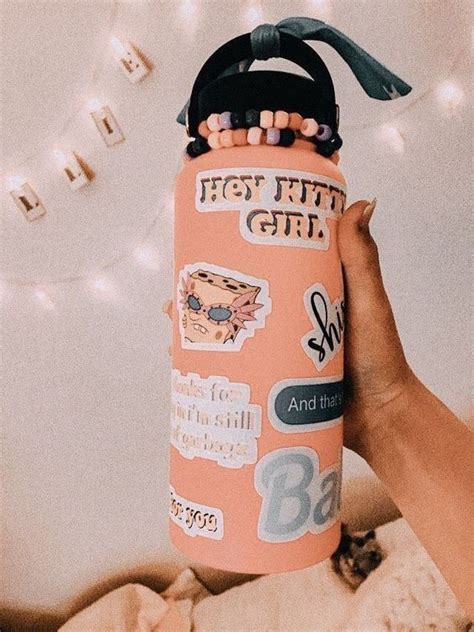 A Person Holding Up A Pink Water Bottle With Stickers On It And The Lid