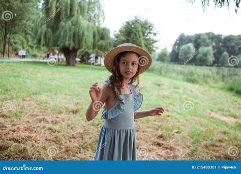 Une Fille En Robe Bleue Et Chapeau De Paille Se Tient Sur La Rive Du