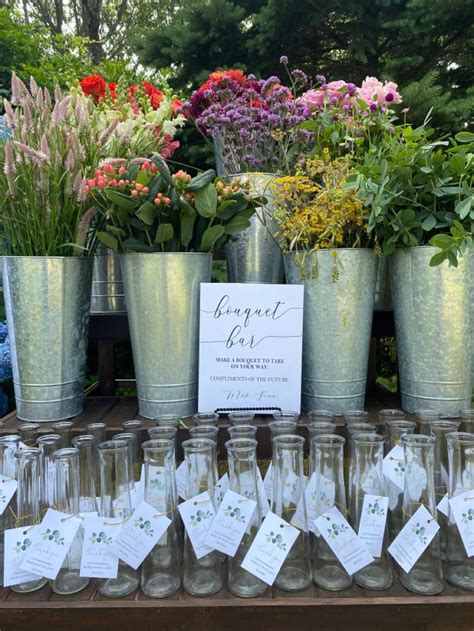 A Table Topped With Lots Of Glass Vases Filled With Flowers And Cards