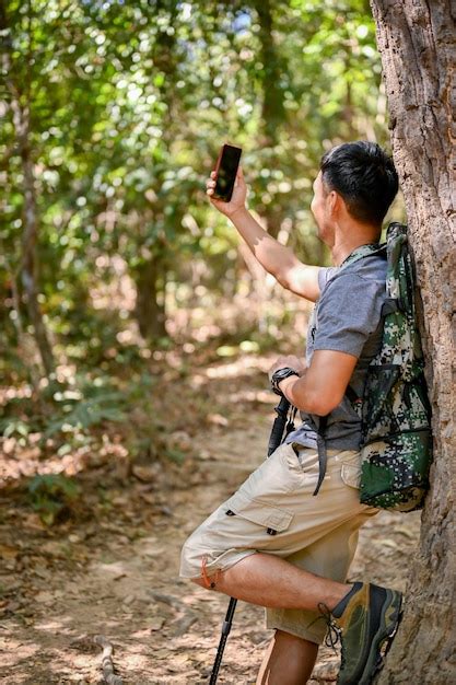 Premium Photo Chilling Asian Male Trekker Leaning Against A Tree