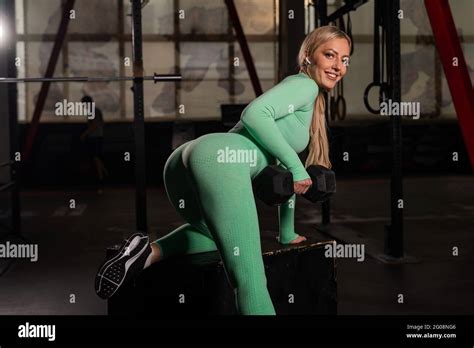 Junge schöne Frau auf der Bank eine einarmige Hantel Rückenübung macht Athletisch blonde
