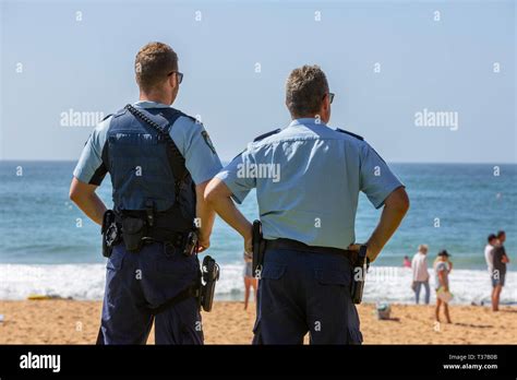 Two New South Wales Police Officers Watch A Surf Rescue Recovery On