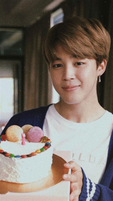 A Young Man Holding A Cake With Frosting And Candies On It In Front Of Him