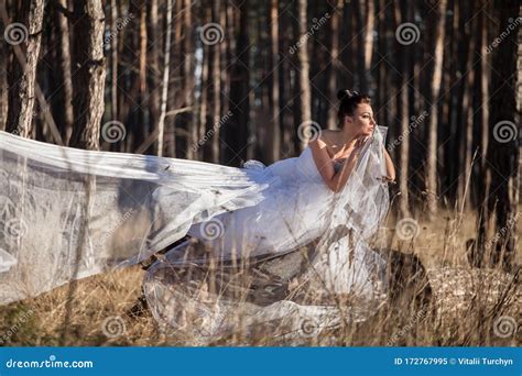 Woman In A White Wedding Dress Stands In The Forest Stock Image