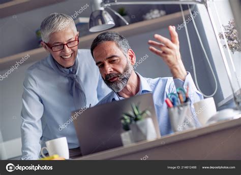 Two Mature Business People Using Laptop Talking Smiling While Working ...