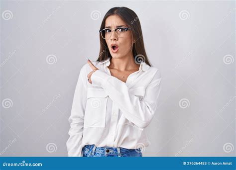 Young Brunette Woman Wearing Glasses Surprised Pointing With Finger To The Side Open Mouth