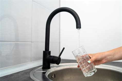 Mano Cortada De Una Mujer Llenando Agua En Un Vaso Del Grifo Foto Premium