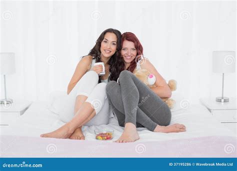 Happy Young Female Friends With Coffee Cups In Bed Stock Photo Image