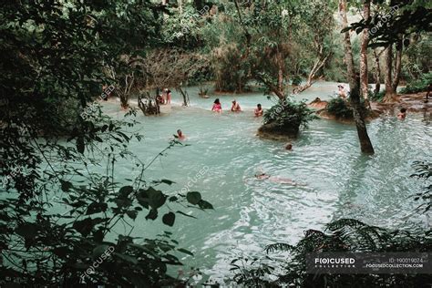 LAOS, LUANG PRABANG: People swimming in blue water of forest lake ...