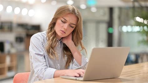 Tired Businesswoman With Laptop Having Neck Pain In Office Stock Photo