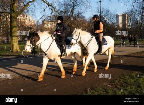 Two People Horse Riding In Hyde Park In Central London Uk Following