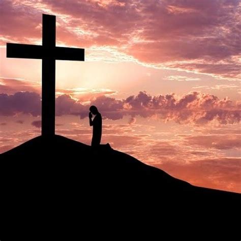 A Person Standing On Top Of A Hill Next To A Cross