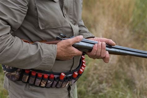 Un Hombre Con Una Pistola En Sus Manos Y Un Chaleco Verde En Una Caza