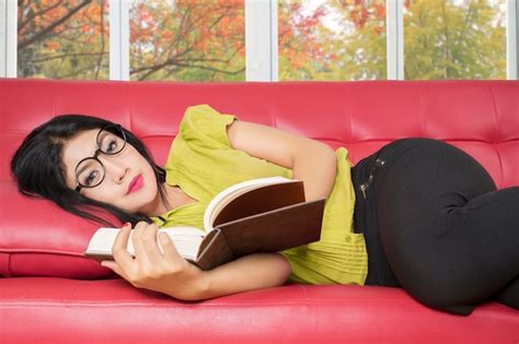 Premium Photo Portrait Of Woman Holding Book While Lying On Sofa