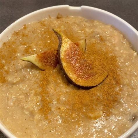 A White Bowl Filled With Oatmeal And Topped With An Orange Peel On Top