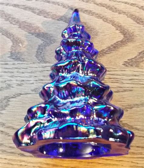 A Purple Glass Christmas Tree Sitting On Top Of A Wooden Table Next To A Wall