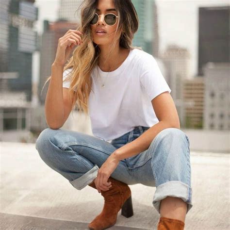 A Woman In White Shirt And Jeans Squatting On The Ground With Her Legs