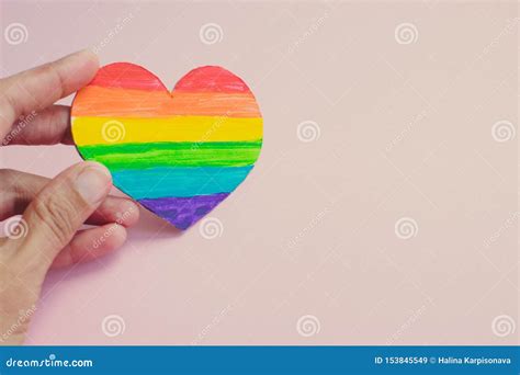 拿着与彩虹条纹的女性手装饰心脏在桃红色背景 Lgbt自豪感旗子，标志的女同性恋，快乐，两性， 库存图片 图片 包括有 艺术 庆祝 153845549