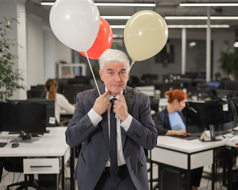 Portrait Of A Cheerful Mature Business Man Holding Balloons In The