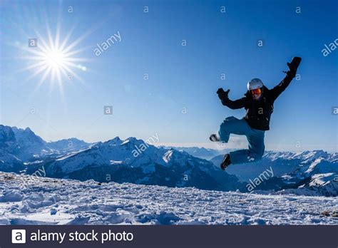 Mädchen mit Brille und Helm springt im Winter in der Luft Blauer