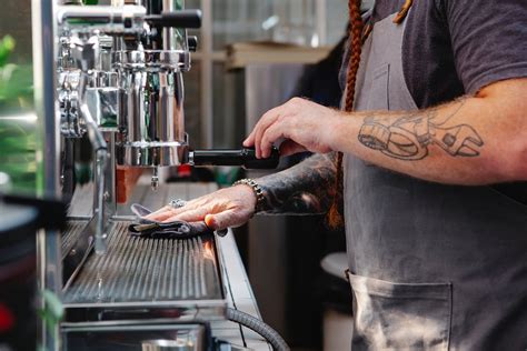 Crop hipster barista cleaning coffee machine in cafe · Free Stock Photo