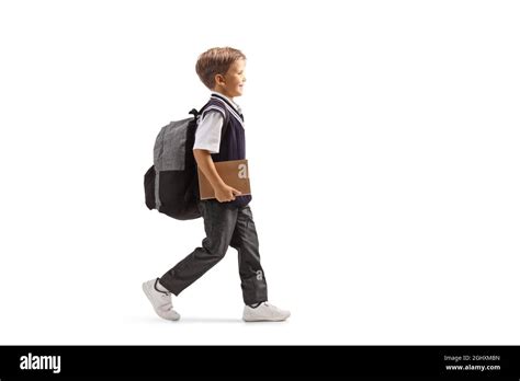 Full Length Profile Shot Of A Little Schoolboy In A Uniform Carrying A