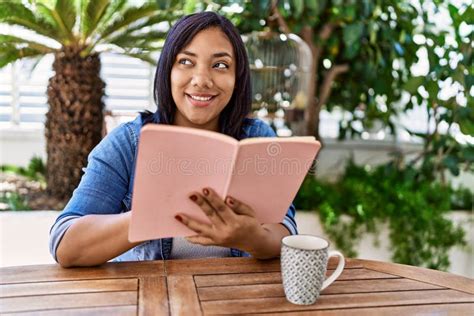 Hispanic Brunette Woman Sitting Reading A Book At The Terrace Stock