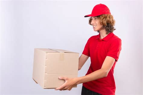 Repartidor joven en uniforme rojo dando caja de cartón a un cliente