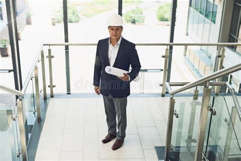 Mature Businessman And Architect With Blueprint In Office Building For