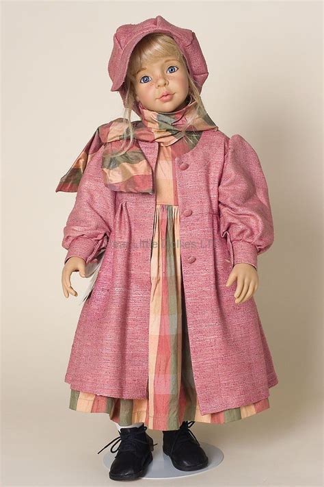 A Doll Wearing A Pink Coat And Hat