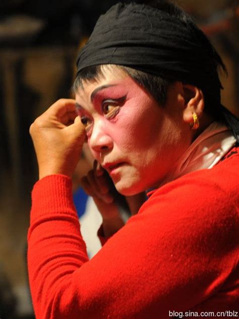 A Woman With Red Makeup And Black Headband Holding Her Hand Up To Her Face