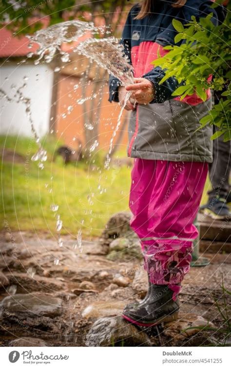 Lightness A Girl Squirts Water With A Water Hose A Royalty Free