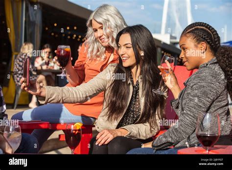 Group Of Young Co Workers Hanging Out On Outdoor Patio Having Drinks