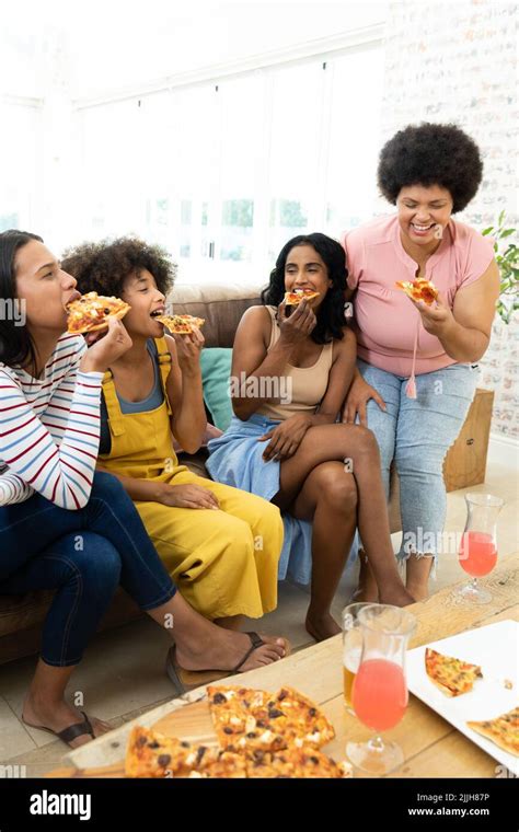 Millennial Biracial Friends Enjoying Pizza And Drinks While Spending