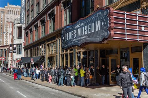 A Group Of People Standing In Front Of A Building With A Sign That Says