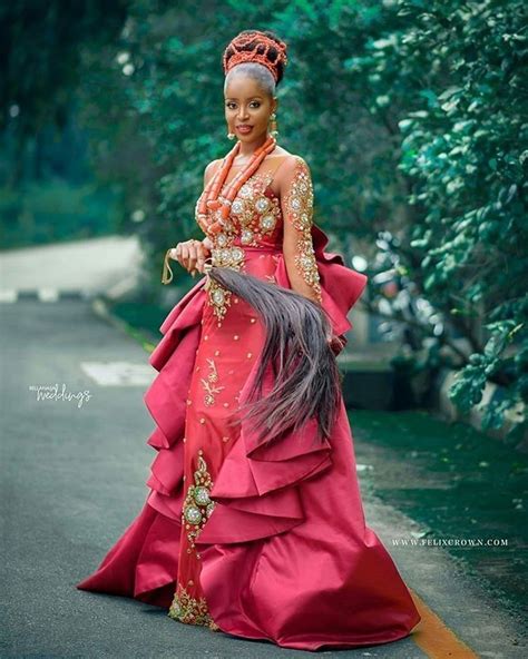 A Woman Is Walking Down The Street In A Red Dress With Feathers On Her Head