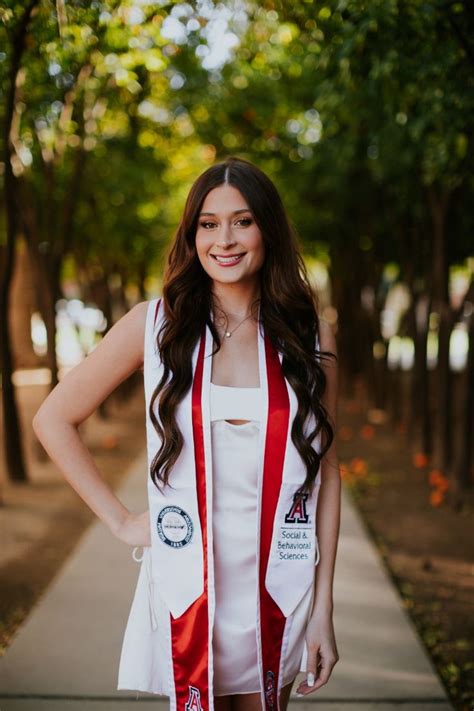 A Woman Standing On A Sidewalk Wearing A Red And White Sash