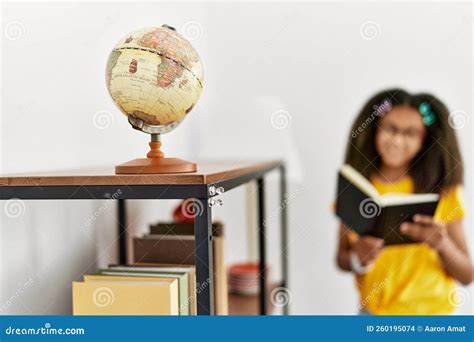 African American Girl Smiling Confident Reading Geography Book At Home