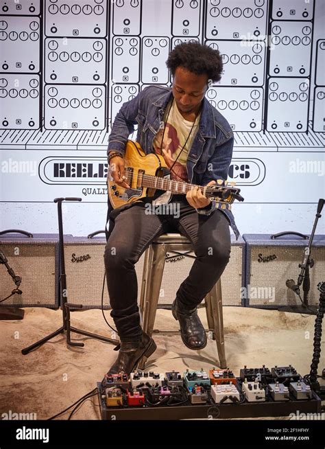 Black Male Electric Guitar Player Sitting On Stool Playing Keeley