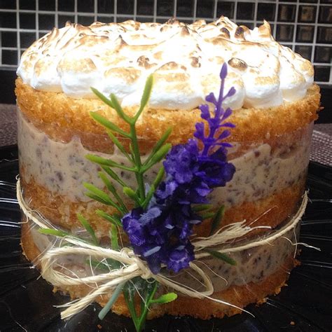 A Cake With Frosting And Purple Flowers On The Top Is Sitting On A