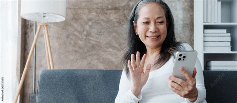 Using Mobile Video Call Happy Asian Mature Woman People Relaxing While Sitting On A Couch