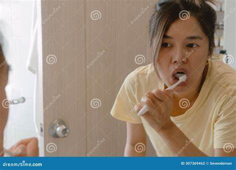 Asian Thai Woman Holding Toothbrush And Brushing Teeth Looking At The