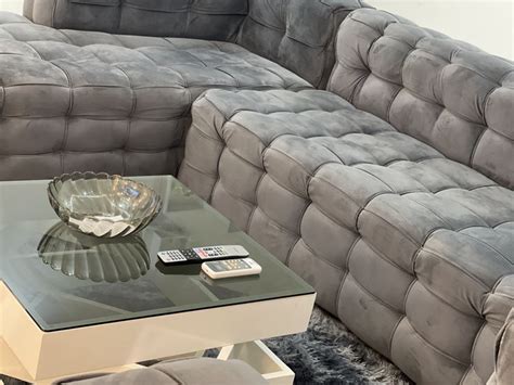 A Glass Table Sitting In Front Of A Gray Couch