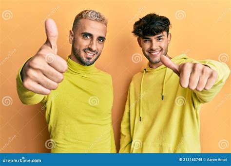 Homosexual Gay Pareja De Pie Juntos Usando Ropa Amarilla Aprobando Hacer Gesto Positivo Con Los