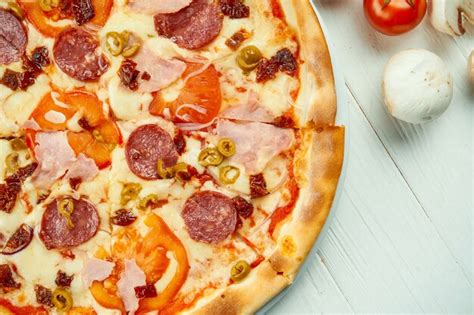 Pizza italiana con salami jamón y aceitunas en una composición con