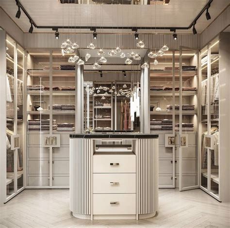 A Walk In Closet Filled With Lots Of White Drawers And Lights Hanging